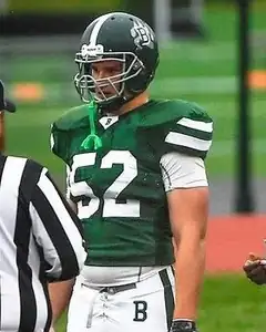 Adam Raine in a green Berkshire School jersey and helmet, standing on the field facing a referee.