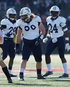 Adam Raine in a white Yale jersey and helmet, moving into position on the field during a game.